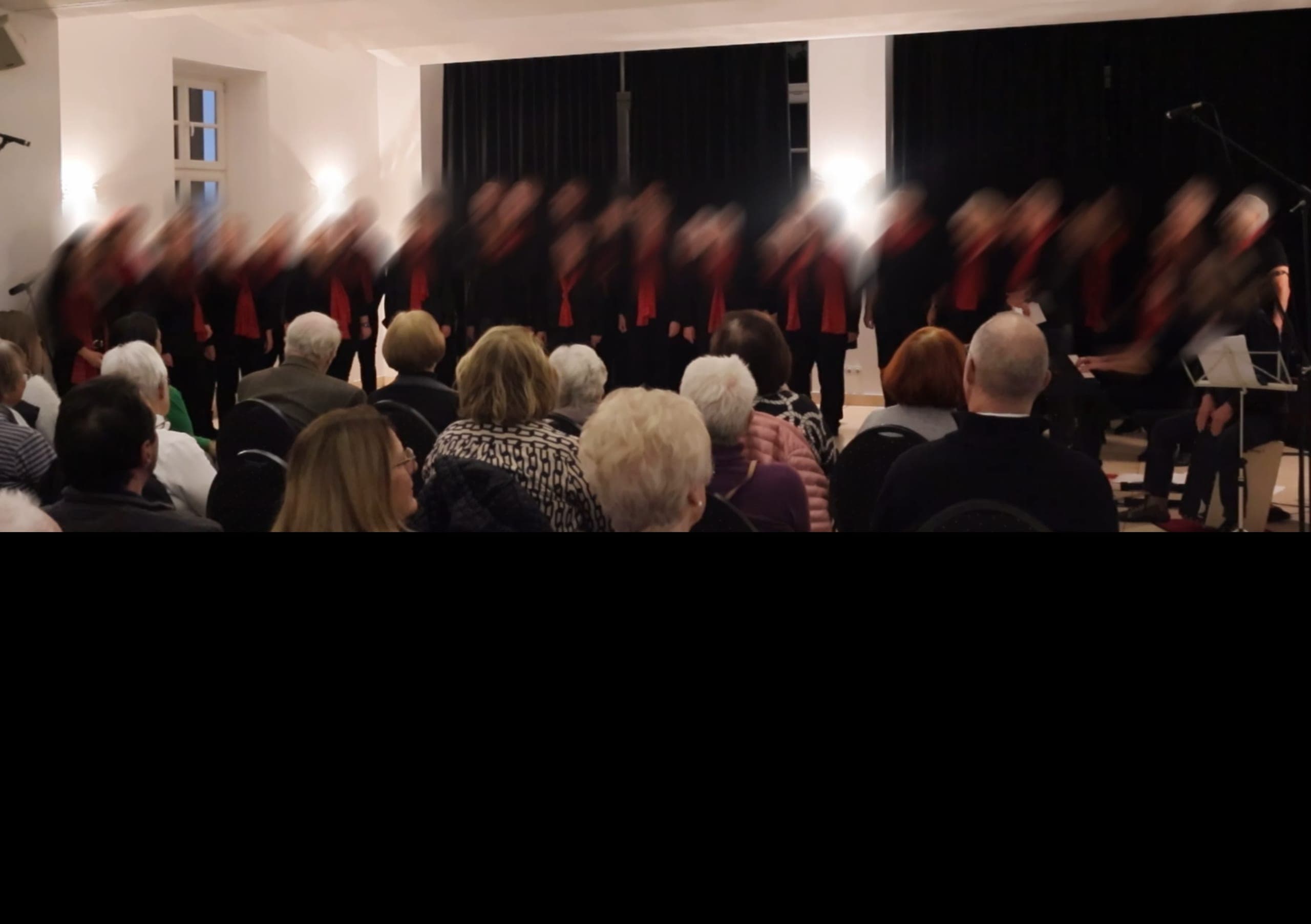 Weiterer Chorauftritt von No Limits im Saal, Gruppe in Schwarz mit roten Akzenten
